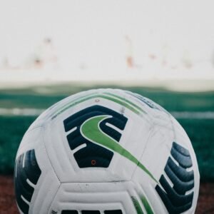Detailed close-up of a soccer ball on a grassy field in daylight.